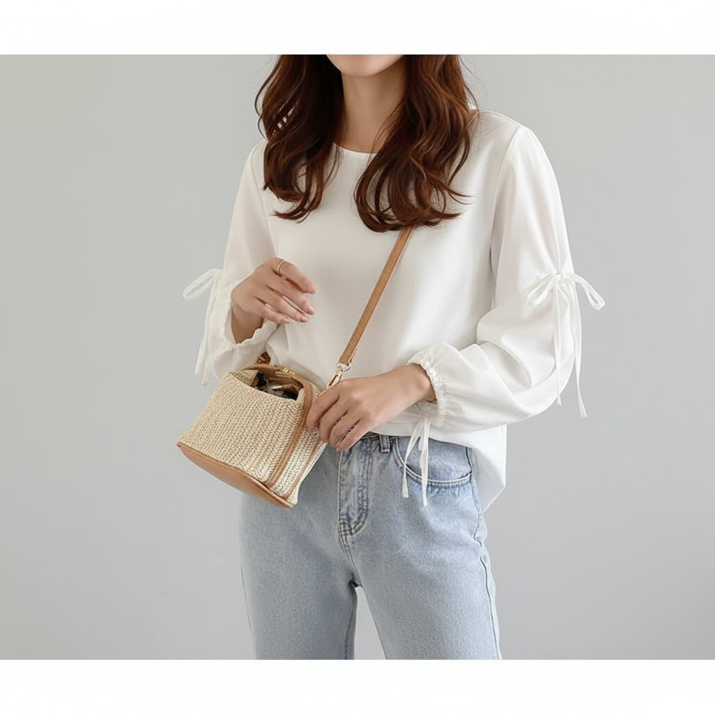 Person wearing a white blouse and light blue jeans with a straw handbag.